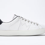 Profil latéral de la chaussure blanche sneaker avec des détails bleu marine et le logo perforé de la couronne sur l'empeigne. Tige en cuir et semelle en caoutchouc blanc.