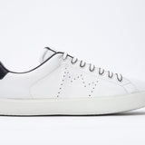 Side profile of low top white sneaker with navy detailing and perforated crown logo on upper. Full leather upper and white rubber sole.
