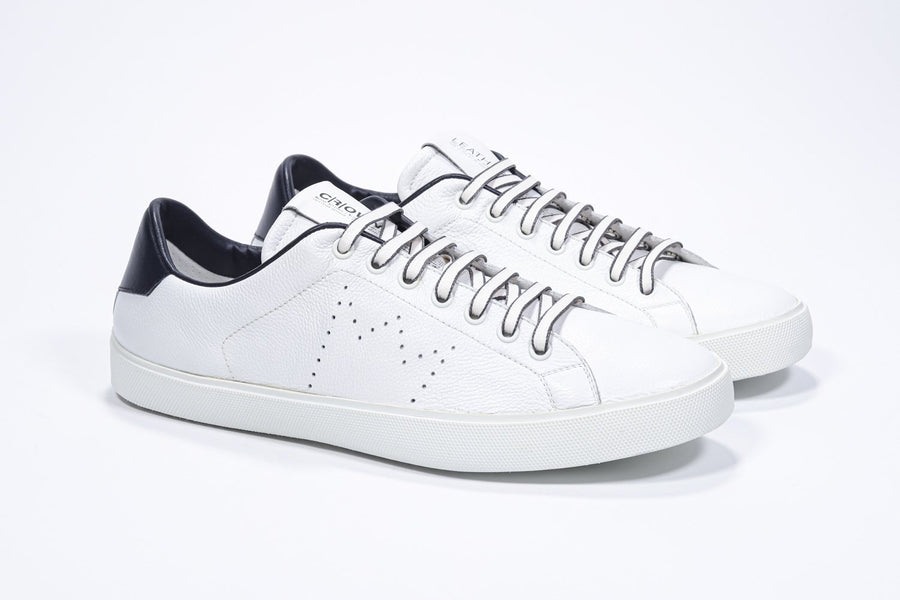 Three quarter front view of low top white sneaker with navy detailing and perforated crown logo on upper. Full leather upper and white rubber sole.
