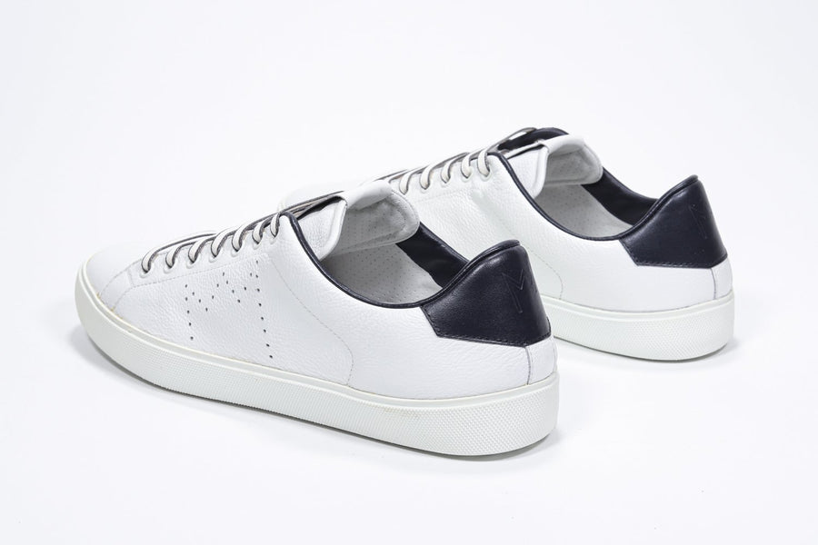 Three quarter back view of low top white sneaker with navy detailing and perforated crown logo on upper. Full leather upper and white rubber sole.