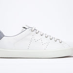 Profil latéral de la chaussure blanche sneaker avec des détails gris clair et le logo perforé de la couronne sur l'empeigne. Tige en cuir et semelle en caoutchouc blanc.
