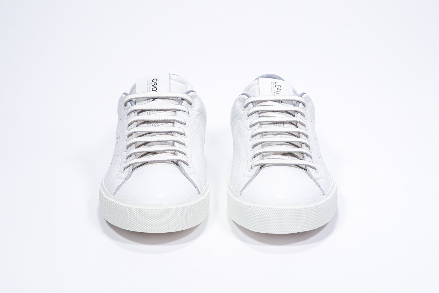 Front view of low top white sneaker with light grey detailing and perforated crown logo on upper. Full leather upper and white rubber sole.