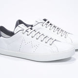 Three quarter front view of low top white sneaker with dark grey detailing and perforated crown logo on upper. Full leather upper and white rubber sole.