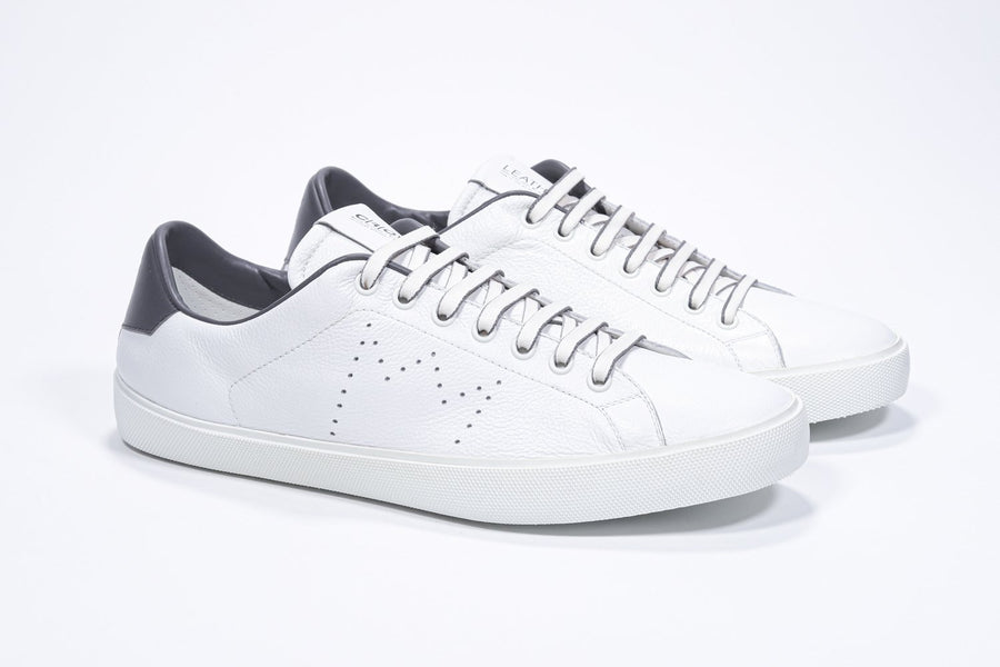 Three quarter front view of low top white sneaker with dark grey detailing and perforated crown logo on upper. Full leather upper and white rubber sole.