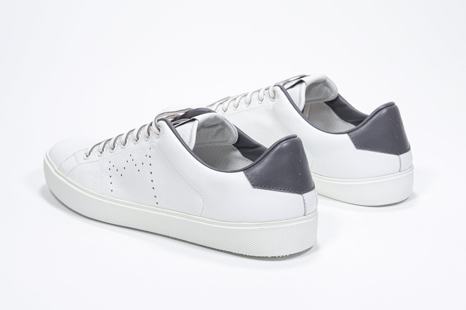 Three quarter back view of low top white sneaker with dark grey detailing and perforated crown logo on upper. Full leather upper and white rubber sole.