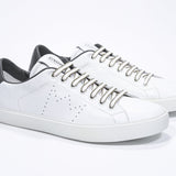 Three quarter front view of low top white sneaker with military green detailing and perforated crown logo on upper. Full leather upper and white rubber sole.