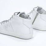 Three quarter back view of mid top white sneaker with full leather upper with perforated crown logo and white sole, and internal zip.