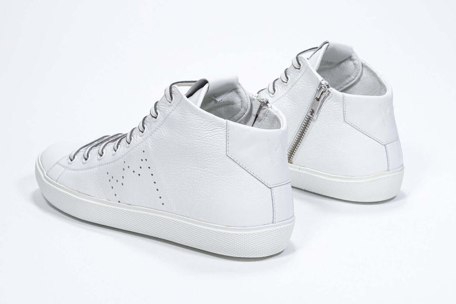 Three quarter back view of mid top white sneaker with full leather upper with perforated crown logo and white sole, and internal zip.