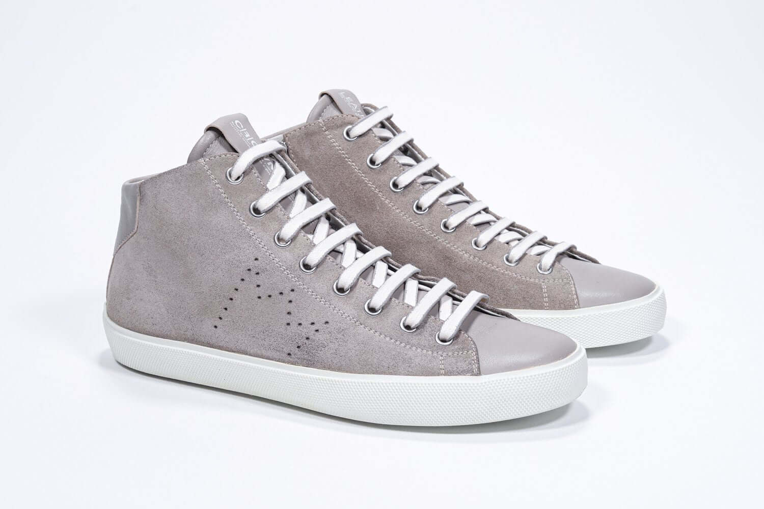 Three quarter front view of mid top beige sneaker with full suede upper with perforated crown logo and white sole.