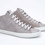 Three quarter front view of mid top beige sneaker with full suede upper with perforated crown logo and white sole.