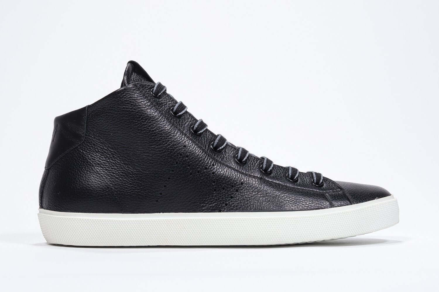 Side profile of mid top black sneaker with full leather upper with perforated crown logo, internal zip and white sole.