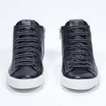 Front view of mid top black sneaker with full leather upper with perforated crown logo, internal zip and white sole.