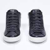 Front view of mid top black sneaker with full leather upper with perforated crown logo, internal zip and white sole.