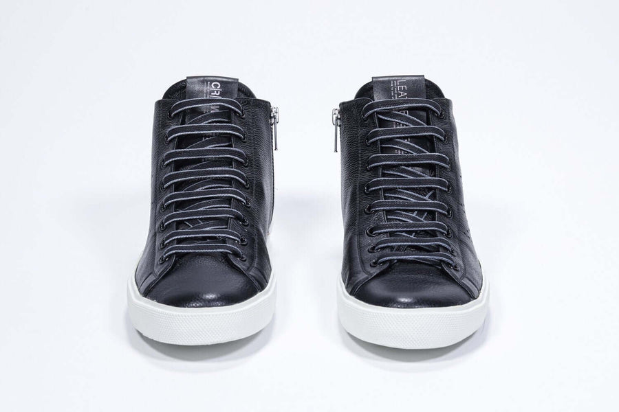 Front view of mid top black sneaker with full leather upper with perforated crown logo, internal zip and white sole.