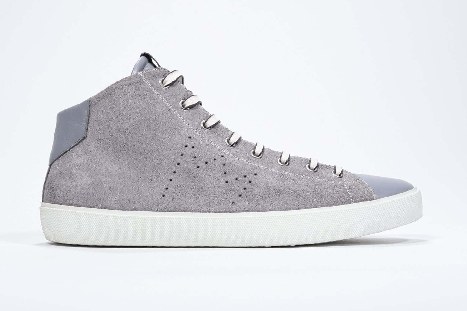 Side profile of mid top light grey sneaker with full suede upper with perforated crown logo, internal zip and white sole.
