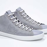 Three quarter front view of mid top light grey sneaker with full suede upper with perforated crown logo, internal zip and white sole.