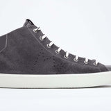 Side profile of mid top dark grey sneaker with full suede upper with perforated crown logo, internal zip and white sole.
