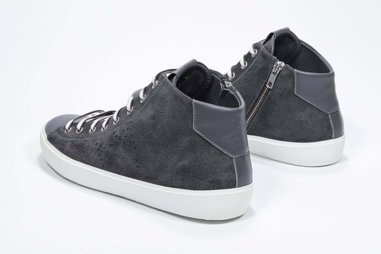 Vista posteriore a tre quarti del modello mid top grigio scuro sneaker con tomaia in pelle scamosciata con logo a corona traforato, zip interna e suola bianca.