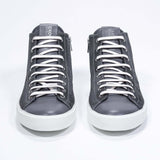 Front view  of mid top dark grey sneaker with full suede upper with perforated crown logo, internal zip and white sole.