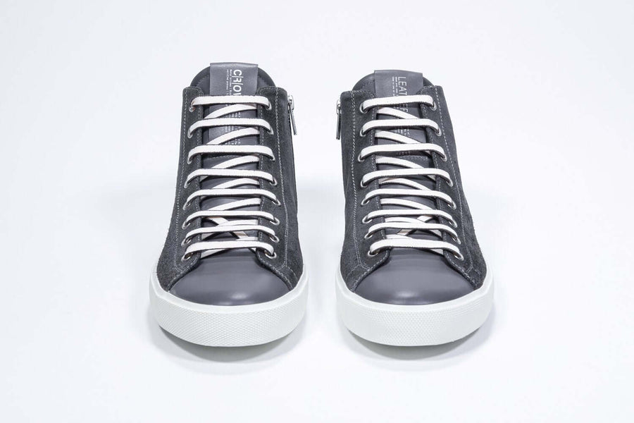 Front view  of mid top dark grey sneaker with full suede upper with perforated crown logo, internal zip and white sole.