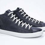 Three quarter front view of mid top navy sneaker with full suede upper with perforated crown logo, internal zip and white sole.