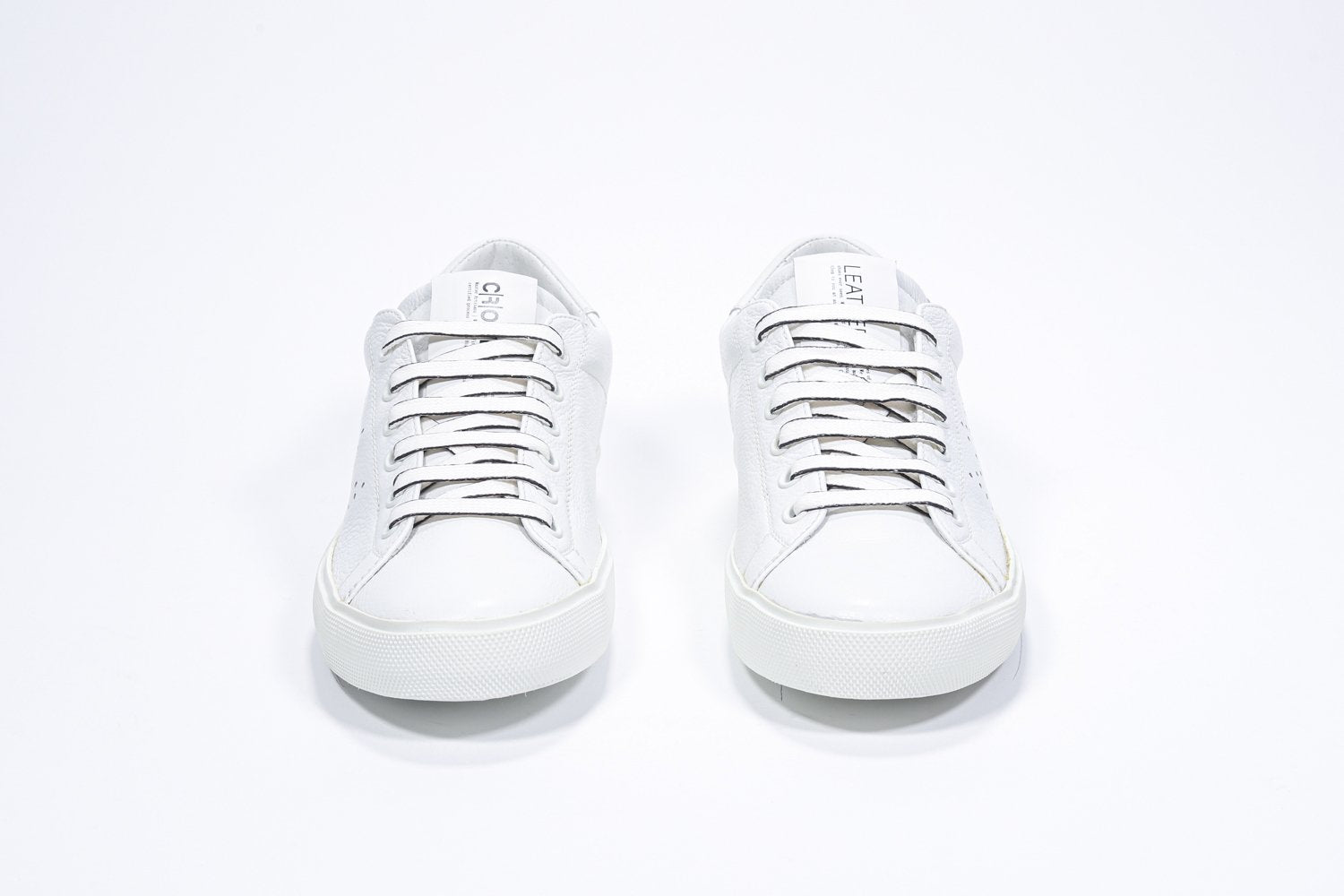 Vue de face de la chaussure blanche sneaker avec le logo perforé de la couronne sur la tige. Tige en cuir et semelle en caoutchouc blanc.