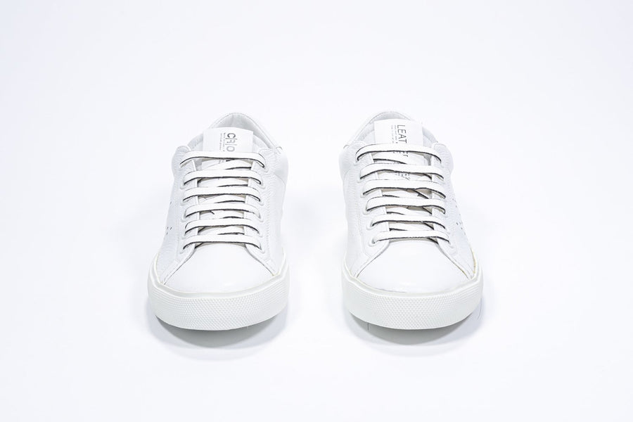 Front view of low top white sneaker with perforated crown logo on upper. Full leather upper and white rubber sole.