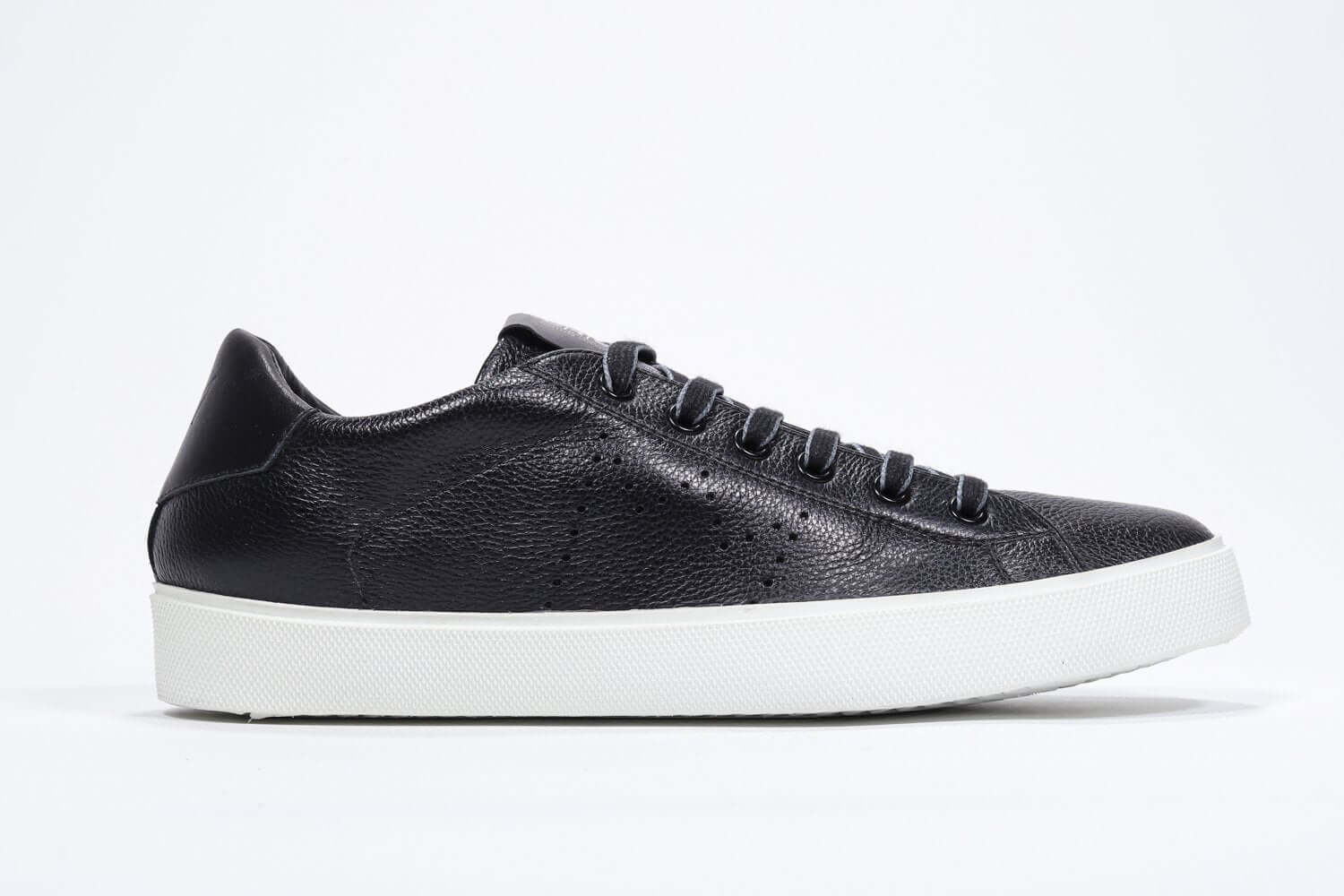 Side profile of low top black sneaker with perforated crown logo on upper. Full leather upper and white rubber sole.