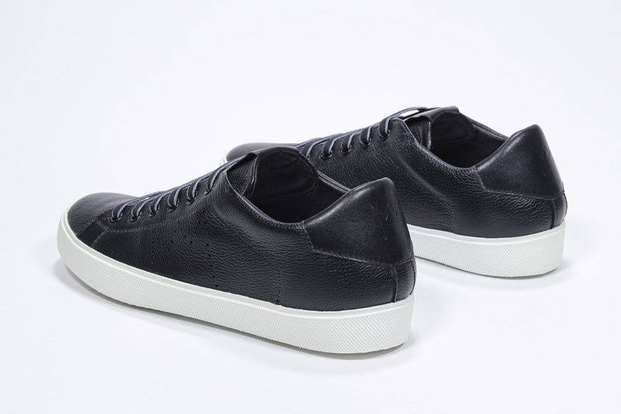 Three quarter back view of low top black sneaker with perforated crown logo on upper. Full leather upper and white rubber sole.