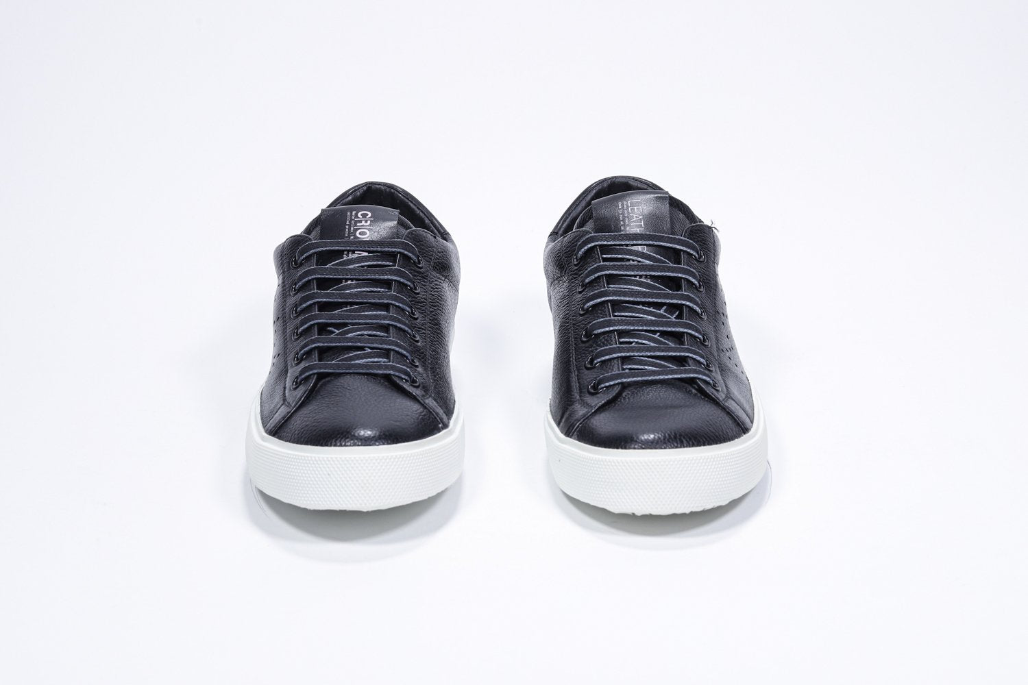 Vista frontale di BASSE nero sneaker con logo della corona traforato sulla tomaia. Tomaia in pelle e suola in gomma bianca.