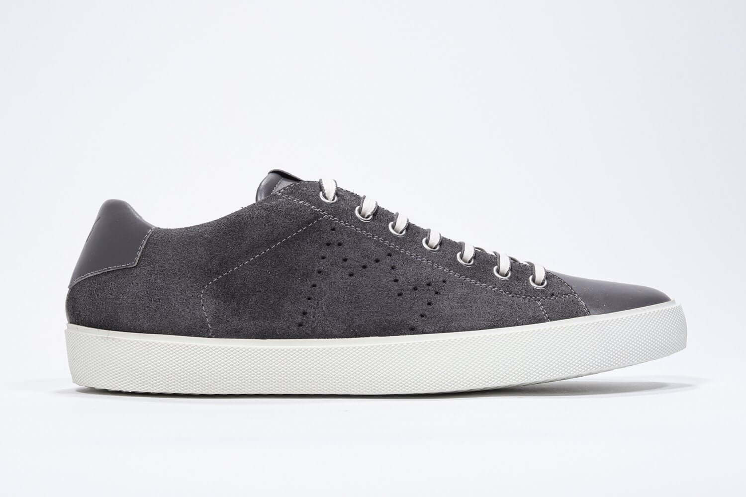 Side profile of low top dark grey sneaker with perforated crown logo on upper. Full suede upper and white rubber sole.