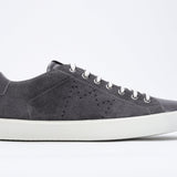 Side profile of low top dark grey sneaker with perforated crown logo on upper. Full suede upper and white rubber sole.