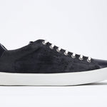 Side profile of low top navy sneaker with perforated crown logo on upper. Full suede upper and white rubber sole.