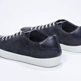 Three quarter back view of low top navy sneaker with perforated crown logo on upper. Full suede upper and white rubber sole.