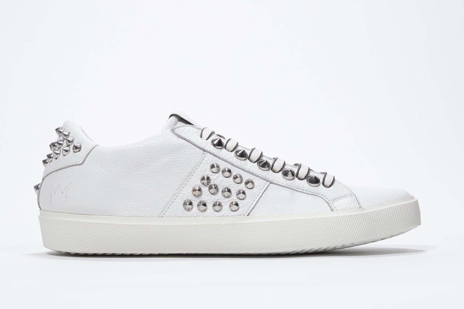 Side view of low top white sneaker. Full grain leather upper with silver studs and white rubber sole.