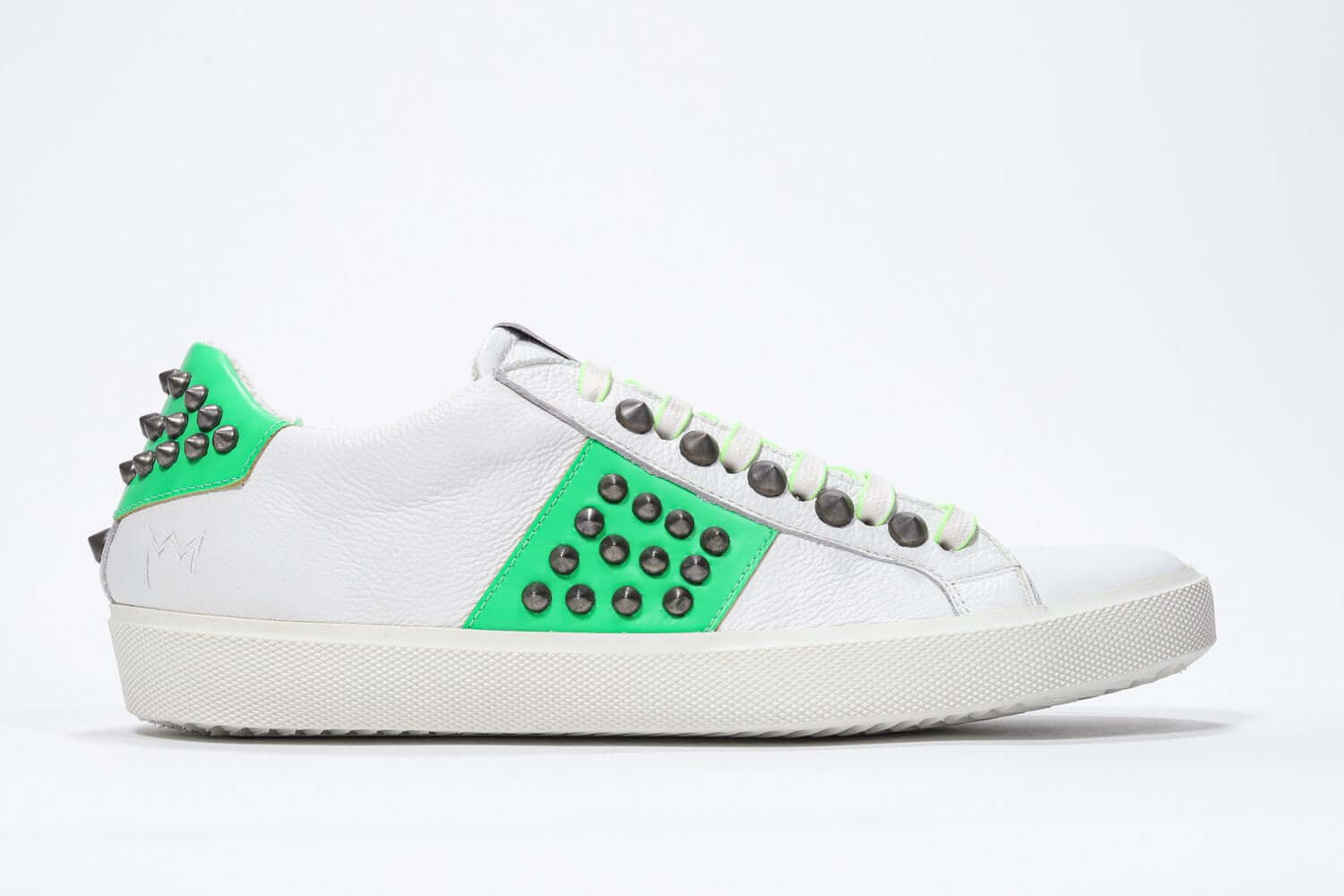 Side profile of low top white and fluo green sneaker. Full grain leather upper with gun metal studs and white rubber sole.