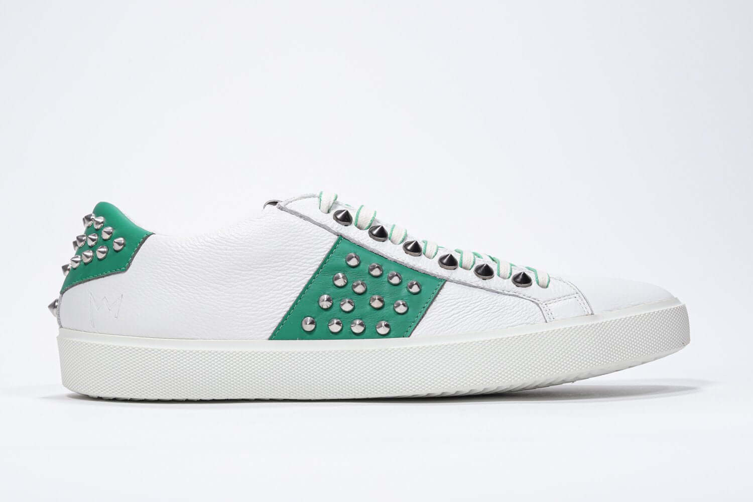 Side profile of low top white and green sneaker. Full grain leather upper with silver studs and white rubber sole.