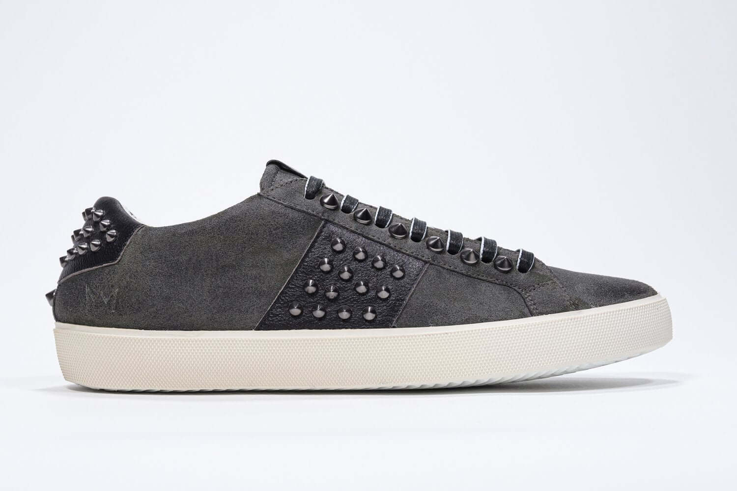 Side profile of low top khaki sneaker. Suede upper with gunmetal studs and vintage rubber sole.