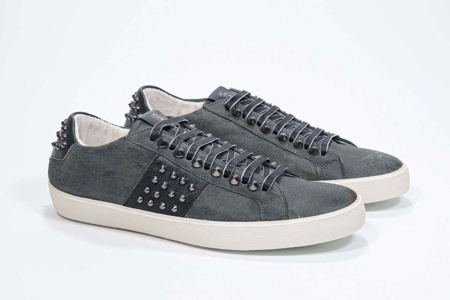 Three quarter front view of low top khaki sneaker. Suede upper with gunmetal studs and vintage rubber sole.