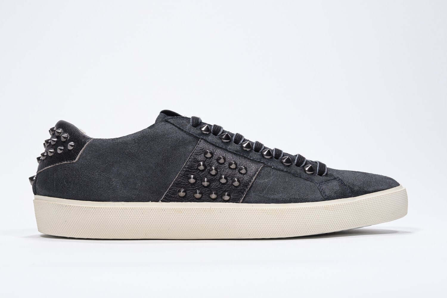 Side profile of low top navy sneaker. Suede upper with gunmetal studs and vintage rubber sole.