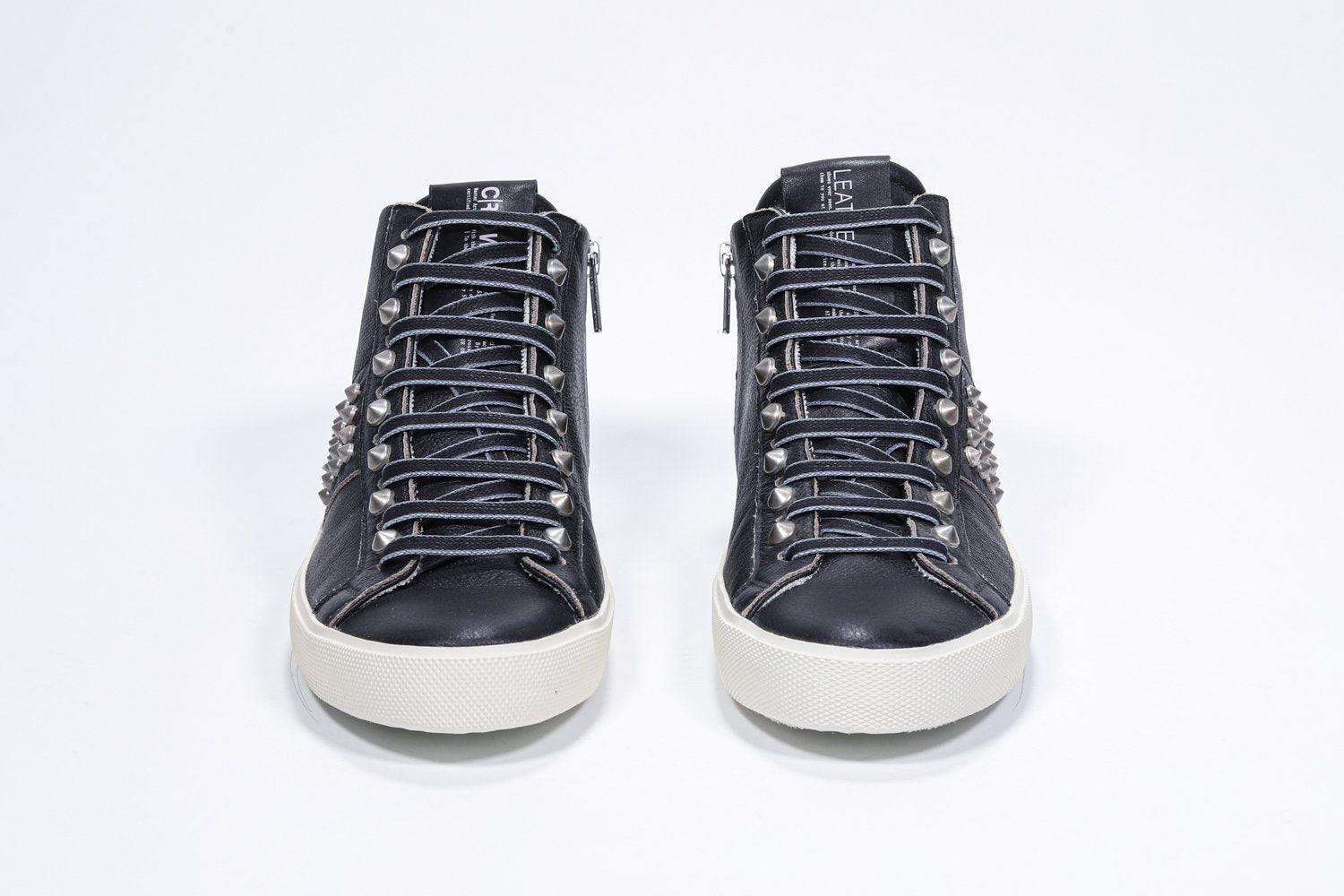 Front view of mid top black sneaker. Full leather upper with studs, an internal zip and vintage rubber sole.