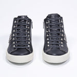 Vue de face d'une paire de chaussures noires sneaker. Tige en cuir avec clous, fermeture à glissière intérieure et semelle en caoutchouc vintage.
