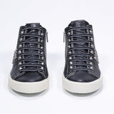 Vue de face d'une paire de chaussures noires sneaker. Tige en cuir avec clous, fermeture à glissière intérieure et semelle en caoutchouc vintage.