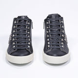 Front view of mid top black sneaker. Full leather upper with studs, an internal zip and vintage rubber sole.