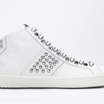 Side profile of mid top white sneaker. Full leather upper with studs, an internal zip and white rubber sole.