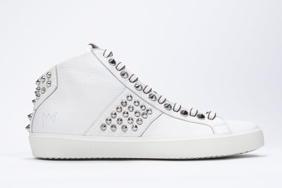 Side profile of mid top white sneaker. Full leather upper with studs, an internal zip and white rubber sole.