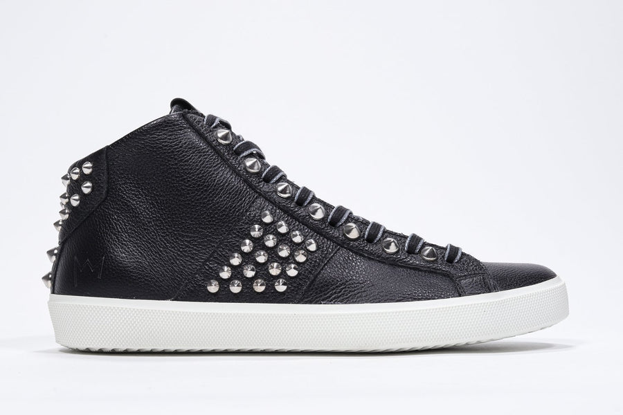 Side profile of mid top black sneaker. Full leather upper with studs, an internal zip and white rubber sole.
