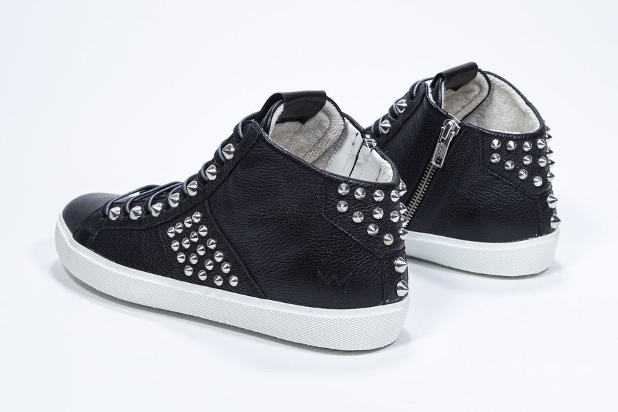 Three quarter back view of mid top black sneaker. Full leather upper with studs, an internal zip and white rubber sole.