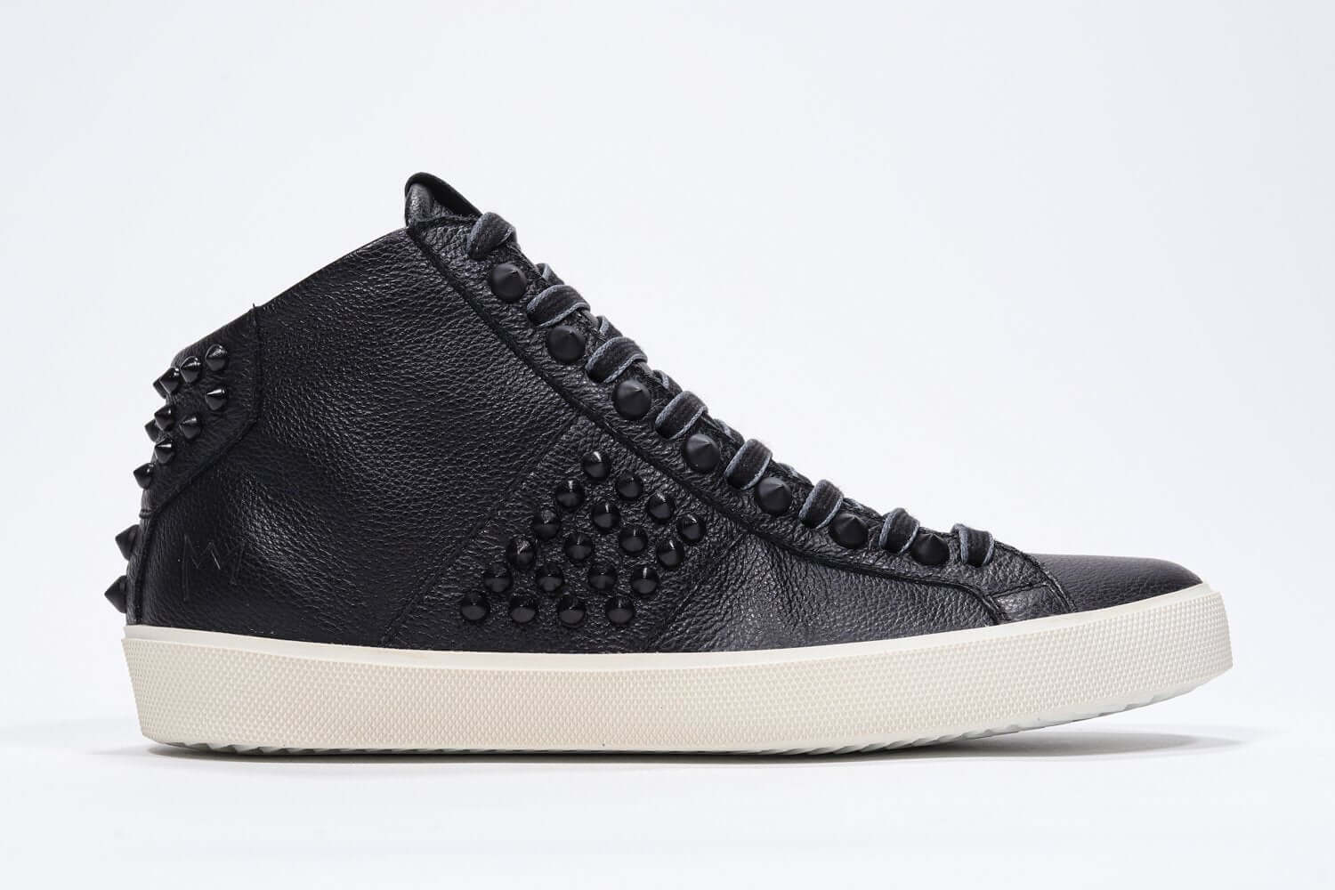 Side profile of mid top black sneaker. Full leather upper with studs, an internal zip and vintage rubber sole.