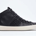 Side profile of mid top black sneaker. Full leather upper with studs, an internal zip and vintage rubber sole.